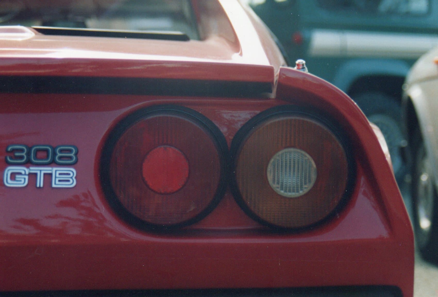 Rear of a red Ferrari 308 GTB featuring signature round taillights and model name emblem.