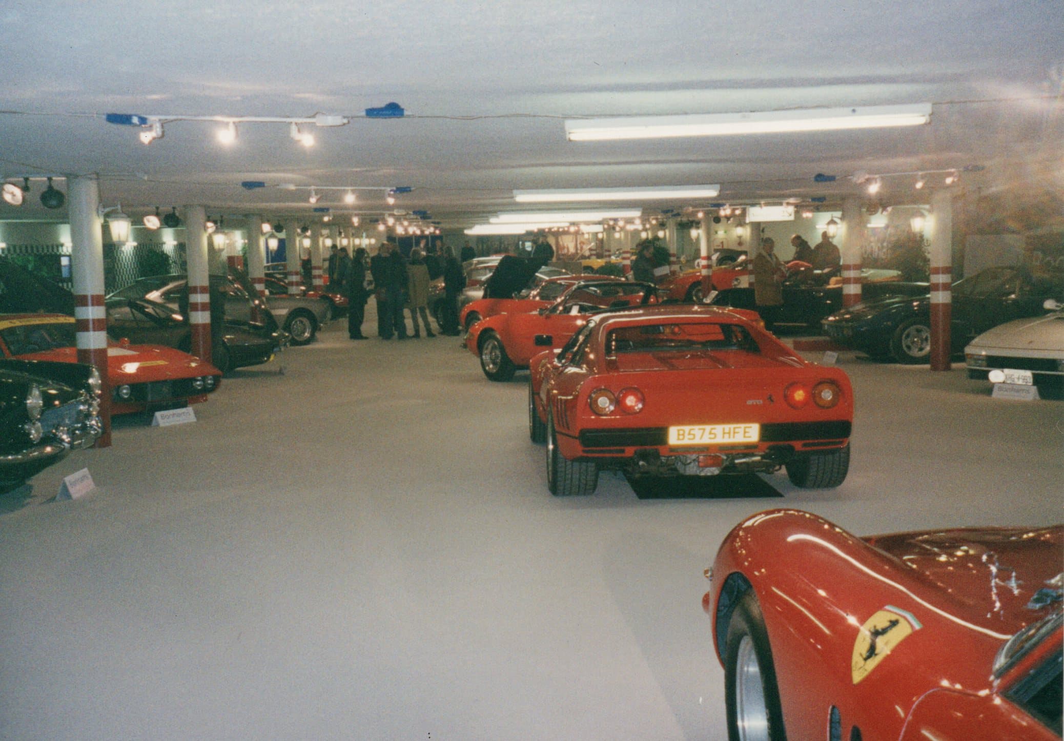 Red Ferrari 288 GTO parked among other classic cars in a brightly lit indoor showroom.